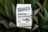 Photo of a bag of Rwanda Nyamasheke Kanzu Wet sitting on large green plant